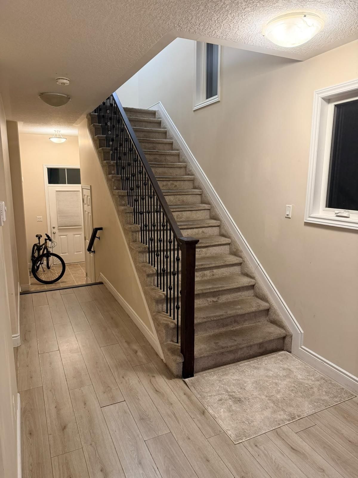 The front hall before: beige walls, a carpeted staircase and the front door at the end