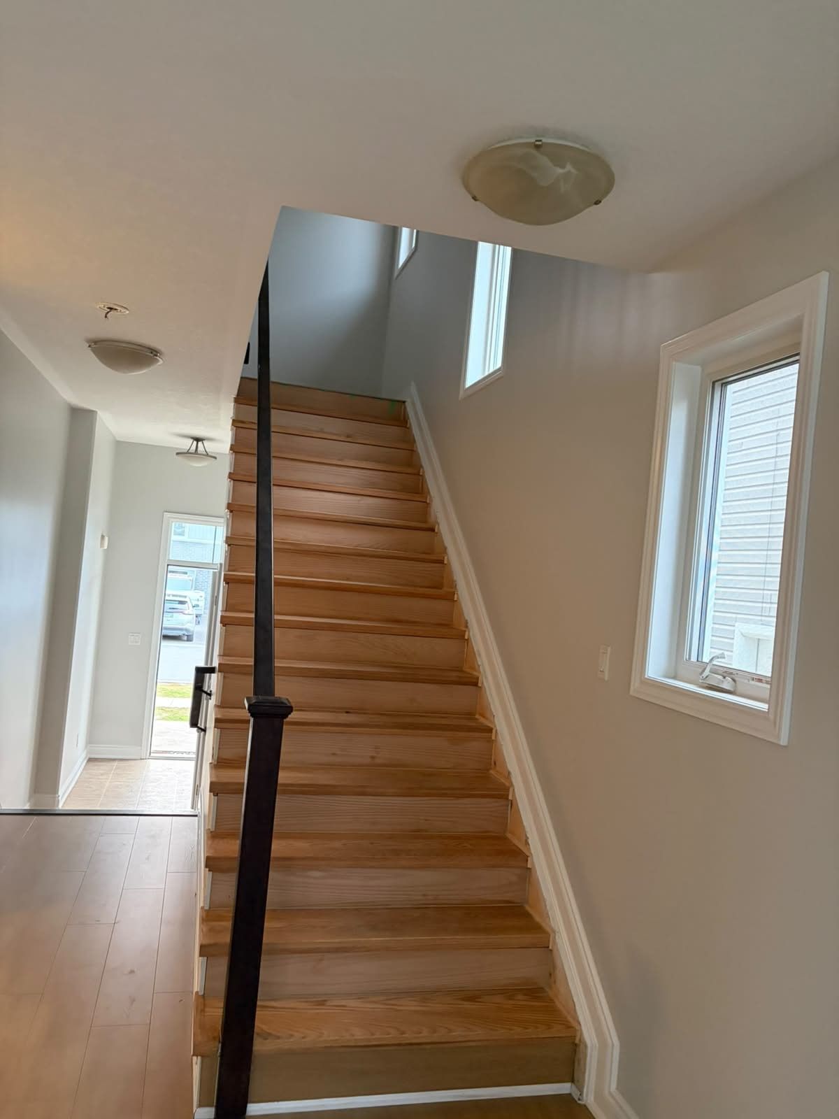 The same stairwell after: light grey walls, white trim and hardwood treads
