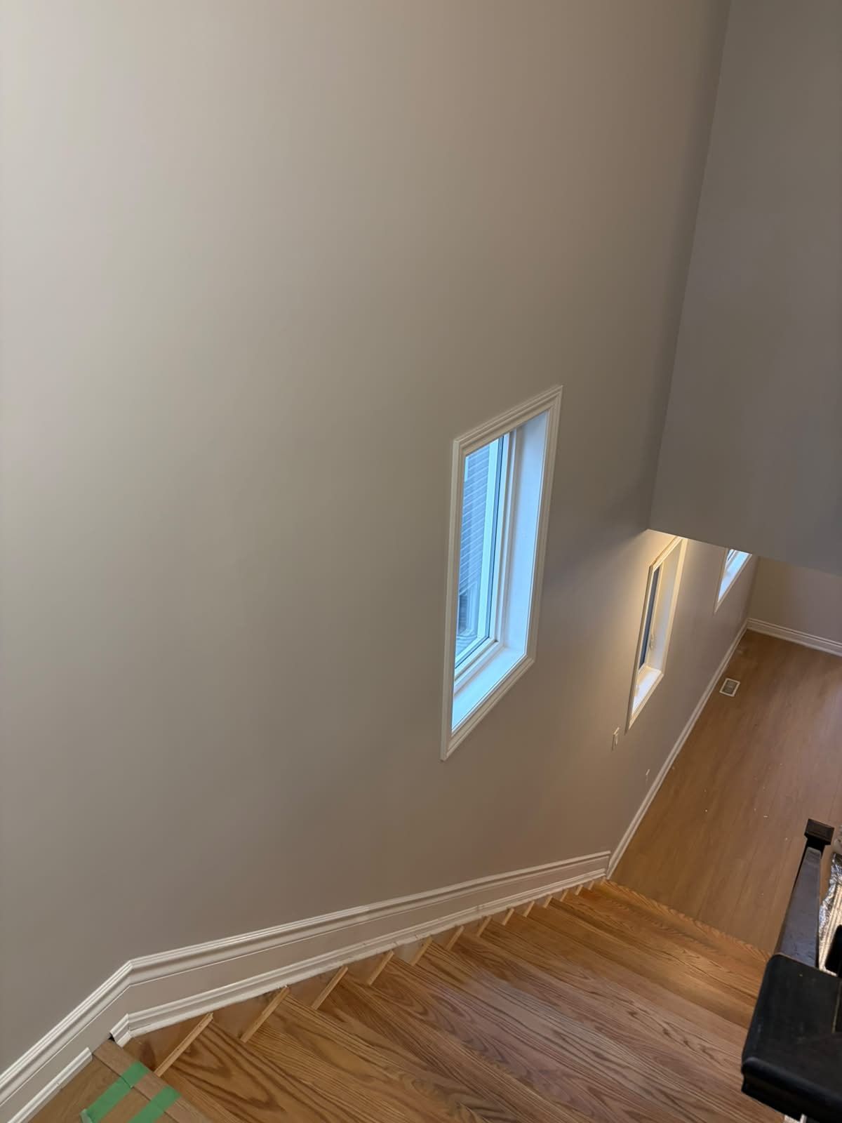 Looking down a stairwell from the upper floor, with a window casing and a clean ceiling line